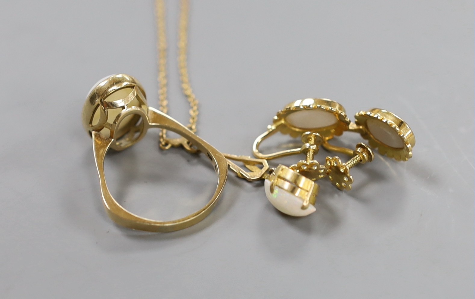 A 750 yellow metal and oval cabochon white opal set ring, size U/V, gross weight 6.2 grams, together with a pair of yellow metal and opal set ear clips and a similar pendant necklace.